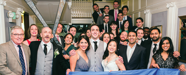 Many guests stand behind a large Brandeis banner at the Parcellin-Li wedding